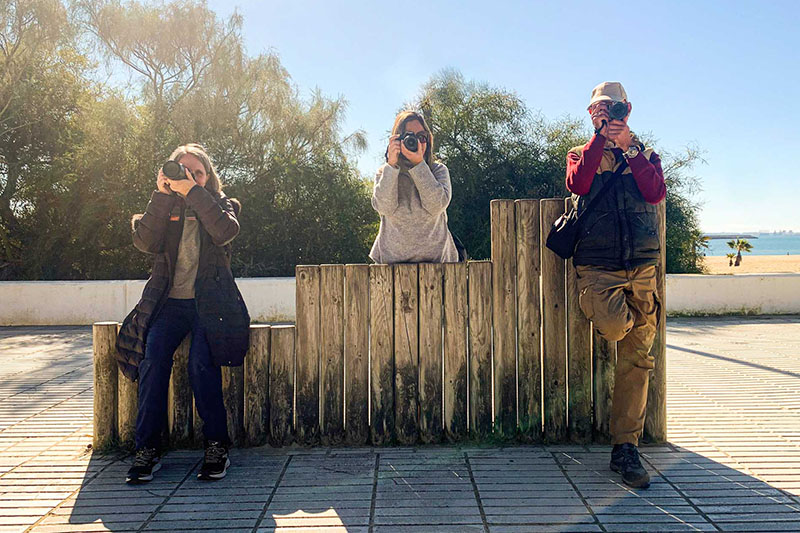 Tres alumnos en diferentes poses haciendo mirando a la cámara mientras hacen fotos en un día soleado